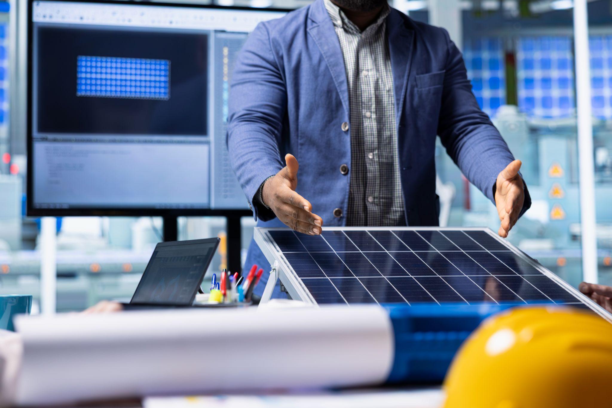 A man in a suit presenting a solar panel in a design office